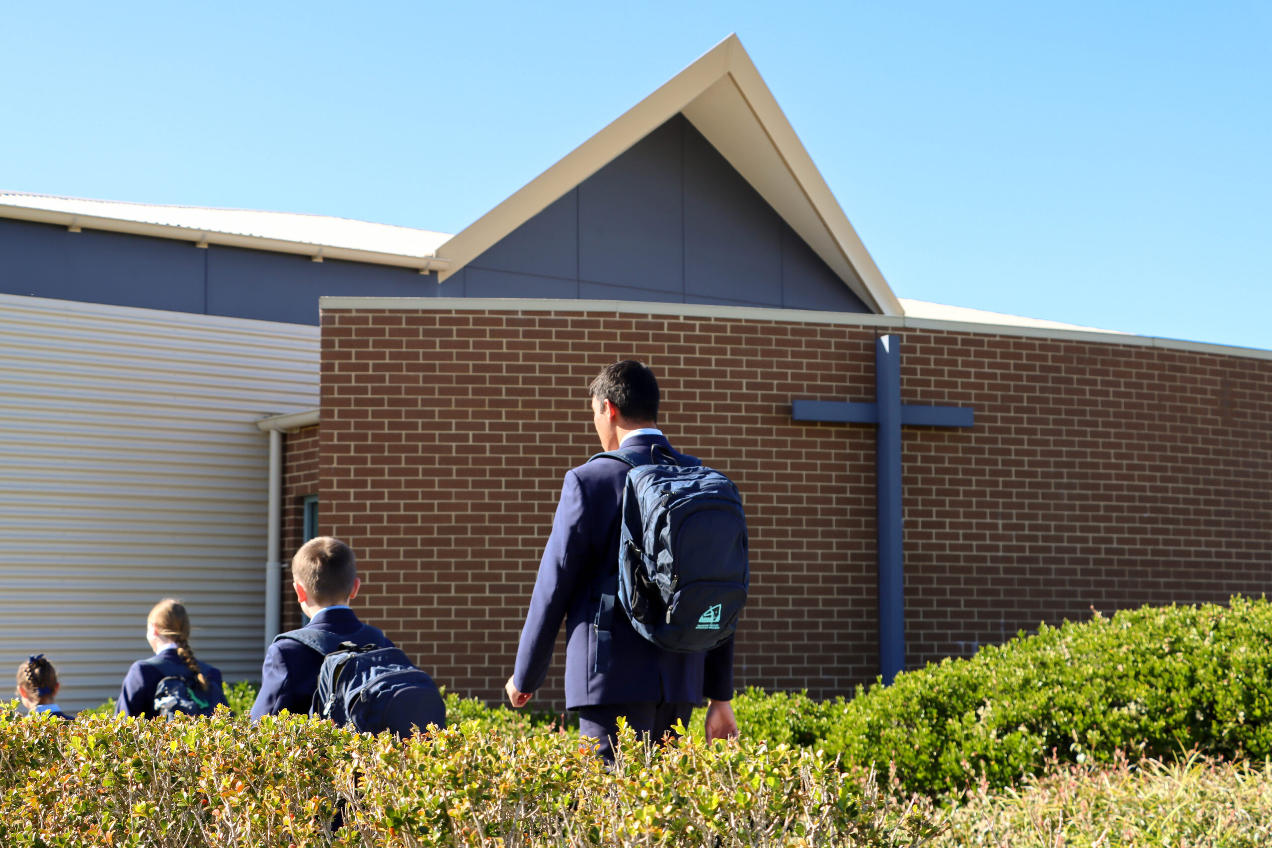 Students enter the school as they walk past the brick curved wall of the hall.