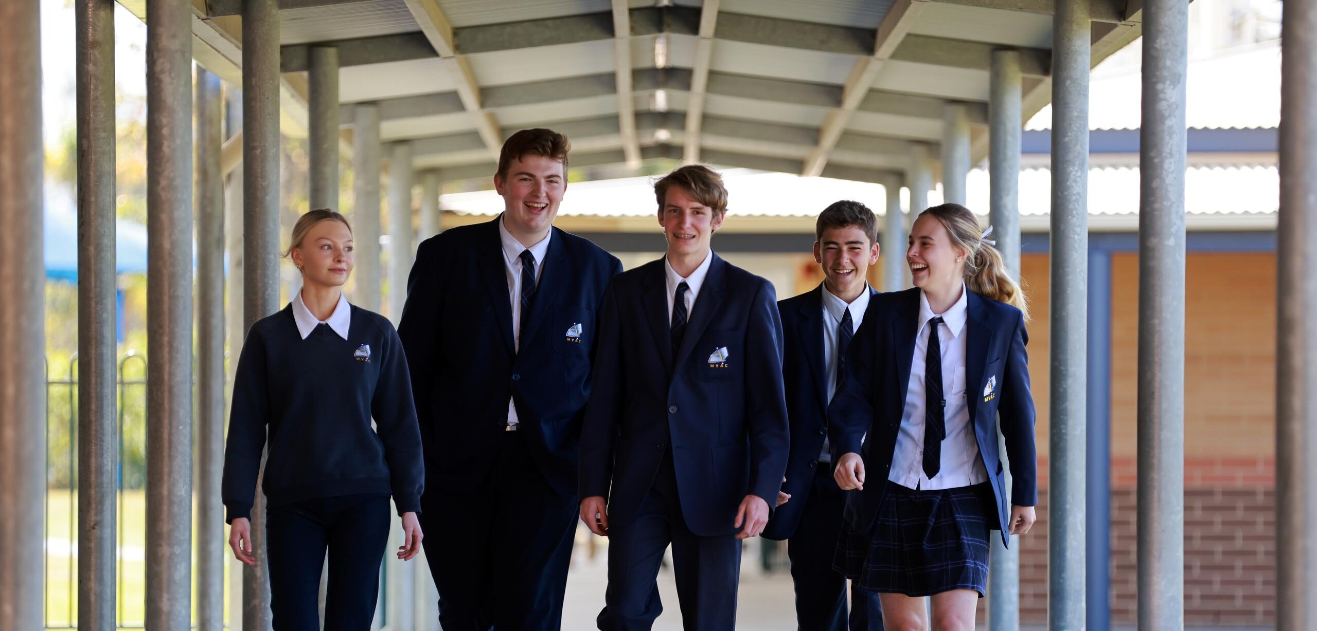 Five Senior Students wearing the Navy College blazer together laughing.