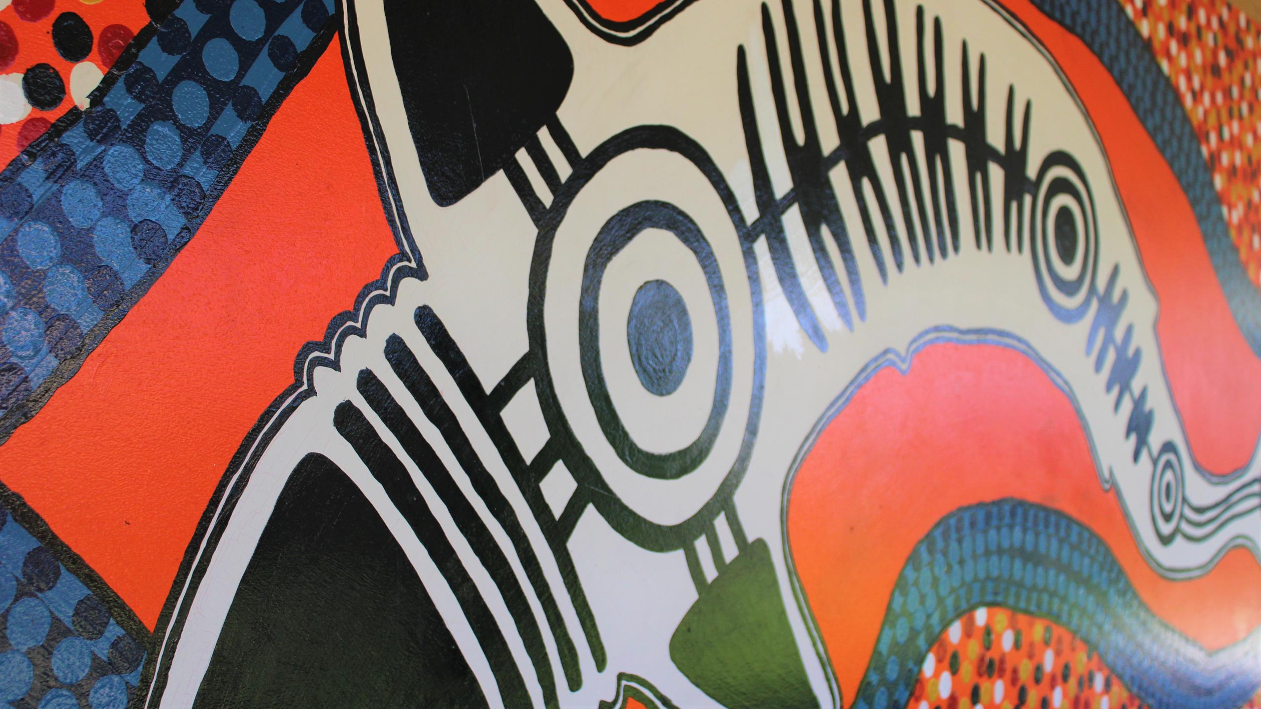 Close up section of the Indigenous mural within the infants area featuring the totem for Biripi Country the - shark. Artwork contains oranges, blues and blacks.