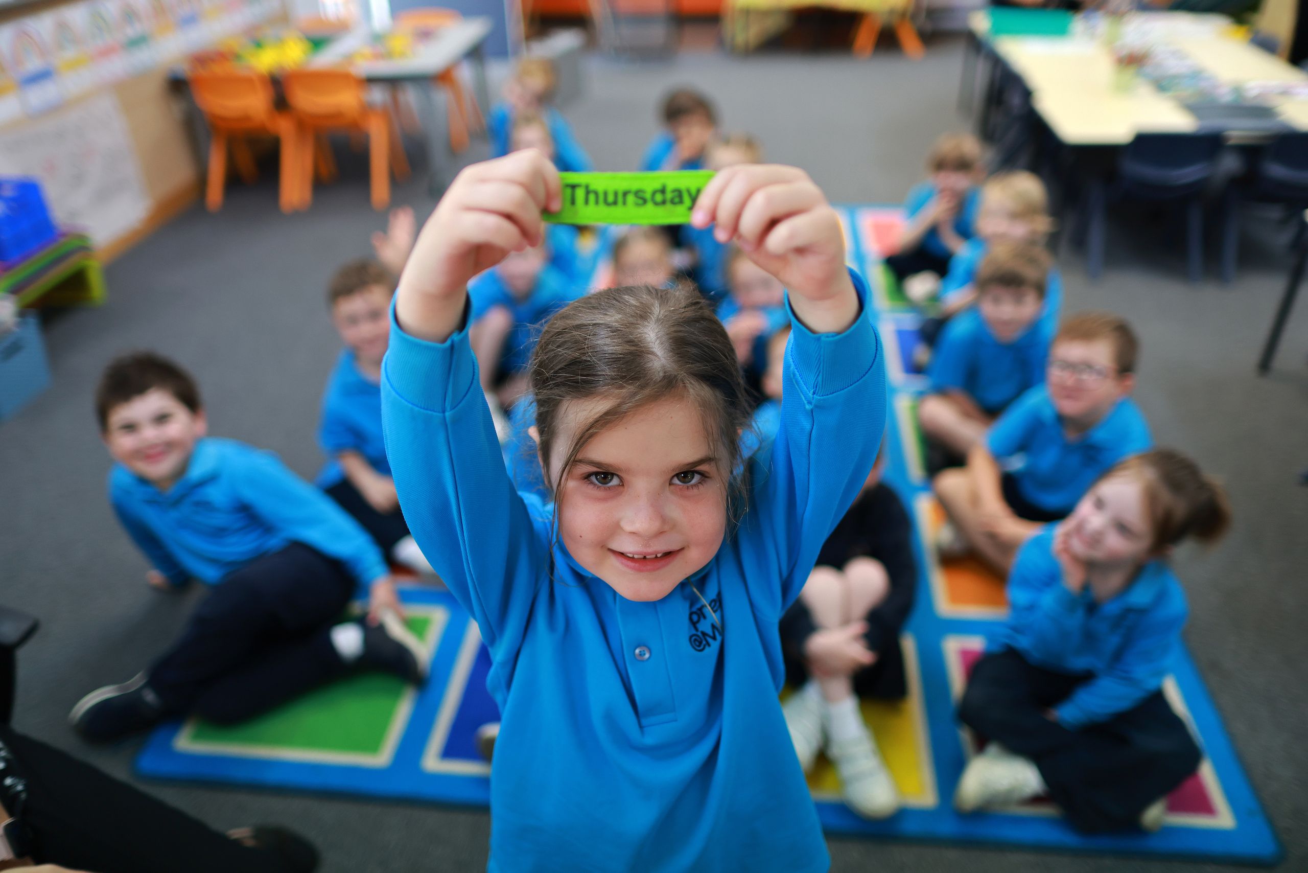 Prep students holds up the name of the day as the students work through their morning calendar routine.