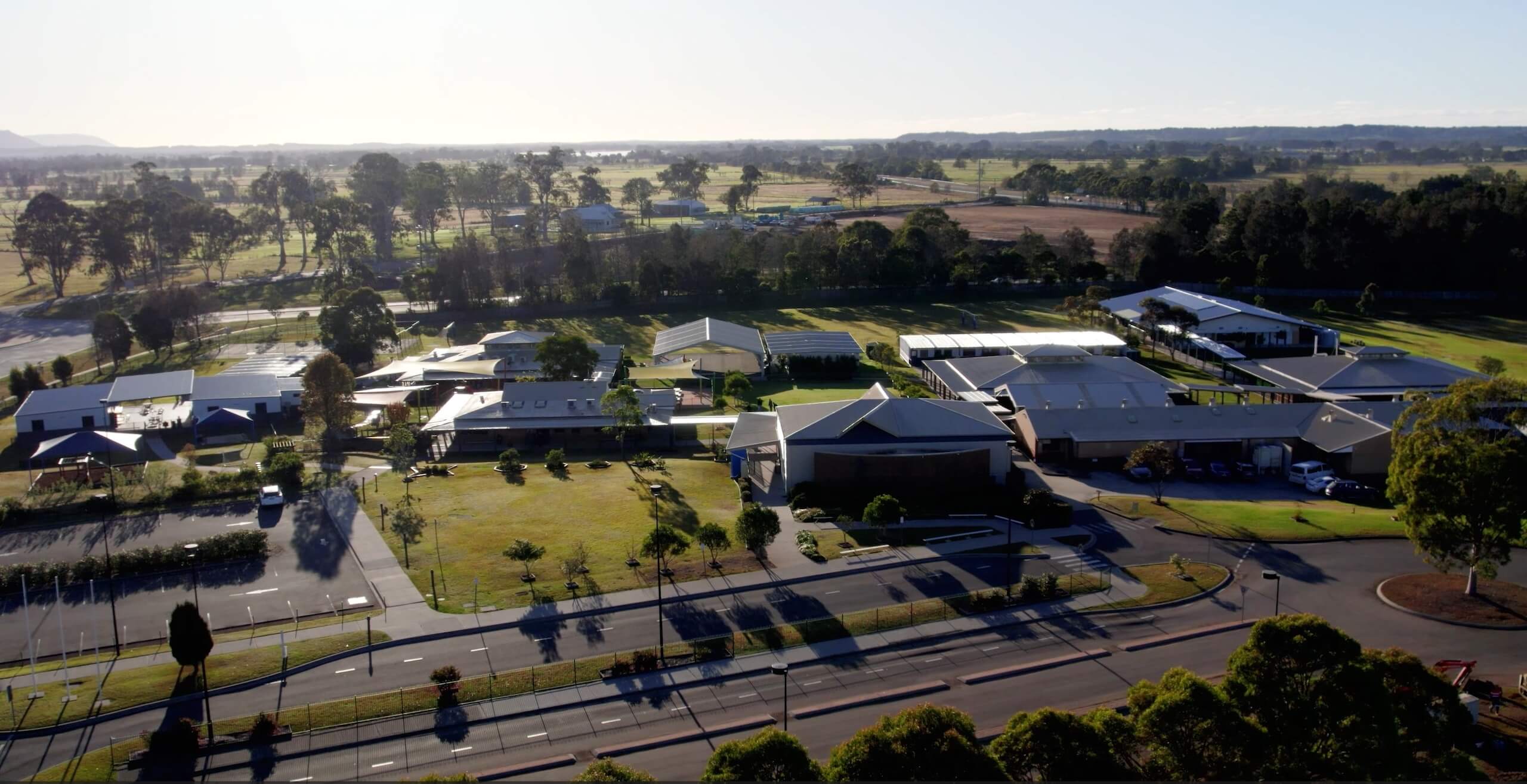 Aerial view of Manning Valley Anglican College and surrounding farmland on a clear sunny day.