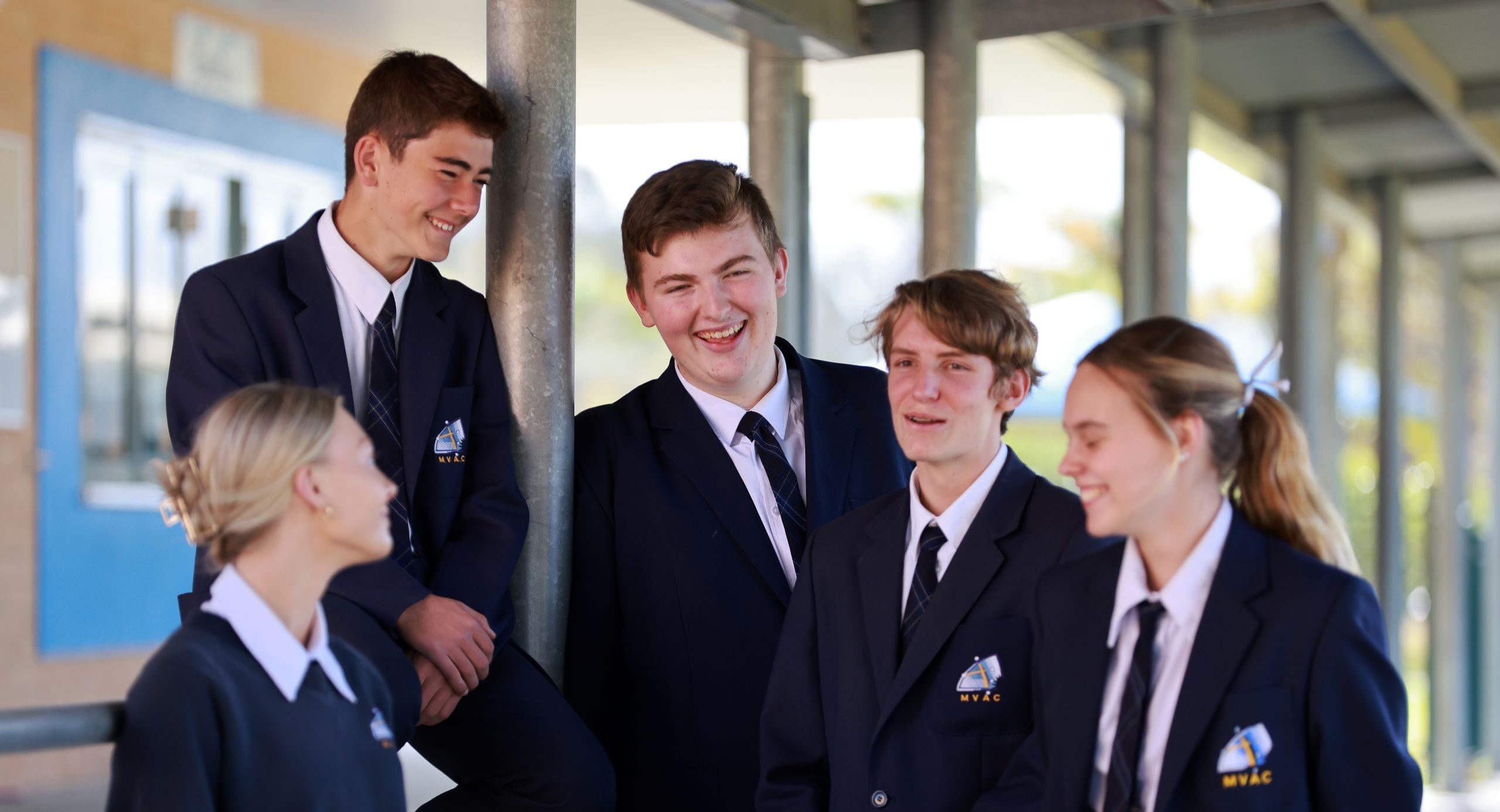 Five Senior Students wearing the Navy College blazer together laughing.